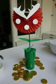 a potted plant sitting on top of a table next to some gold coins and paper flowers