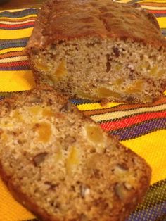 two slices of banana bread sitting on top of a colorful table cloth next to a knife