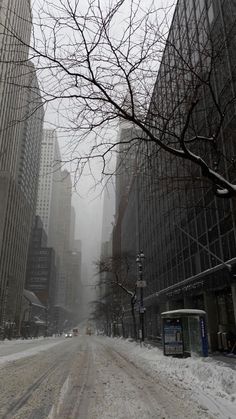 a snowy street with tall buildings in the background