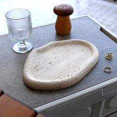 an object is sitting on top of a table next to a glass and ring holder