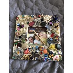 a photo frame covered in buttons and other items on a quilted bed sheet,