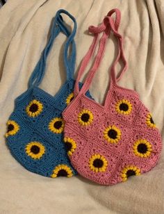 two crocheted sunflower purses sitting on top of a white bed next to each other