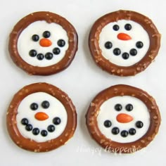 four pretzels with frosting and blueberries in the shape of a snowman