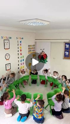 a group of children sitting in front of green chairs