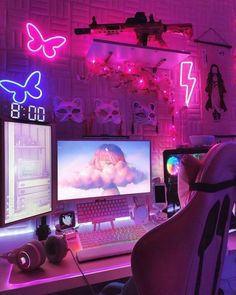 a computer desk topped with two monitors and a laptop next to a neon light wall