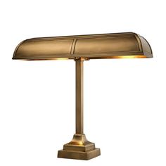 a lamp that is on top of a white surface and has a gold shade over it