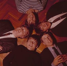 four men are standing in a circle on the floor looking up at the camera and smiling