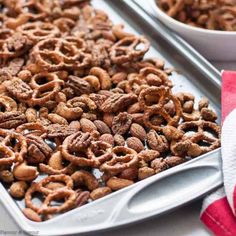 two trays filled with nuts on top of a white table cloth next to red and white napkin