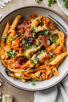 a bowl filled with pasta and sauce on top of a white table next to garlic