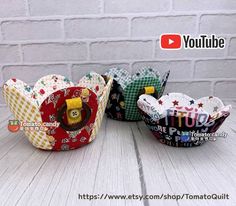 three small baskets sitting next to each other on top of a white wooden table with a brick wall in the background