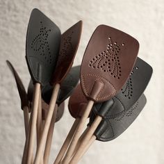 four leather spatulas with wooden sticks sticking out of them on a white surface