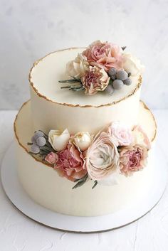 two tiered wedding cake with flowers on each layer and white frosting icing