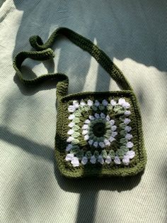 a green crocheted bag sitting on top of a white blanket next to a pillow