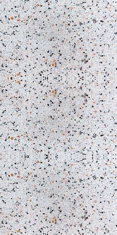 a white surface with black, orange and grey speckles on it's edges