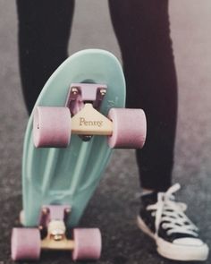 a person standing next to a skateboard with pink wheels