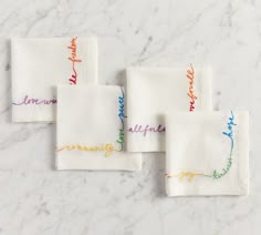 four embroidered napkins on a marble surface