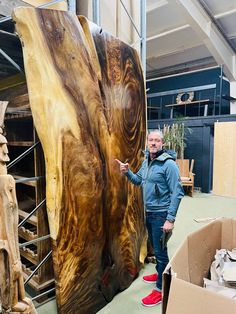 a man standing next to a large piece of wood