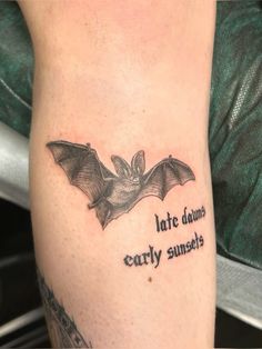 a bat tattoo on the leg with words written below it that reads late dawns early sunsets