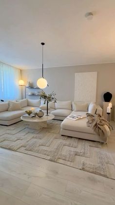 a living room with white couches and tables in the center, along with a large rug on the floor