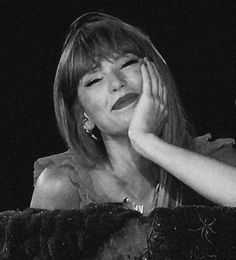 black and white photograph of a woman holding her hand up to her face while sitting in front of a microphone