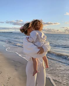 a woman holding a child on the beach