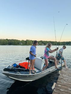 three people on a boat with fishing rods in the water and one person holding a pole