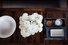 white roses are arranged in the shape of a heart on top of a wooden table