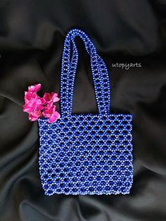 blue beaded purse with pink flower on black satin background, closeup photo by utopygirls