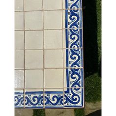 a blue and white tile pattern on the side of a building with grass in the background