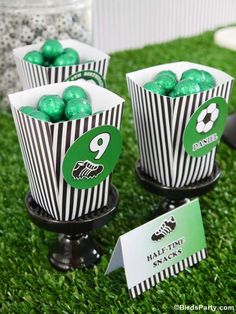 some green and black striped paper cups with candy in them sitting on the grass next to each other