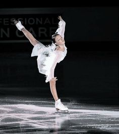 a female figure skating on the ice in a white dress and silver shoes with her arms outstretched