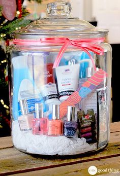 a glass jar filled with lots of beauty products on top of a wooden table next to a christmas tree