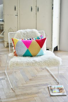 a white chair sitting on top of a hard wood floor next to a magazine rack