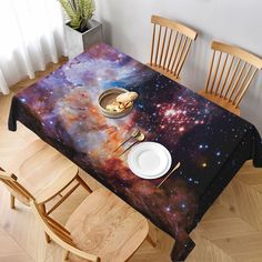 the table is covered with an image of space and stars in the sky, as well as plates and utensils