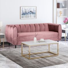 a living room with pink velvet couch and coffee table