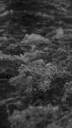 black and white photograph of water with small waves coming up from the rocks in the foreground