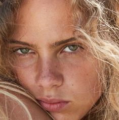 a woman with freckled hair and blue eyes is posing for a photo in front of the camera