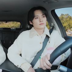 a man sitting in the back seat of a car with his hands on the steering wheel