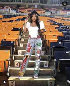 a woman standing on some steps in front of an empty bleachers with numbers painted on her pants