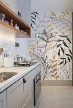 a kitchen with white cabinets and wallpaper decorated with flowers, leaves and plants on the walls