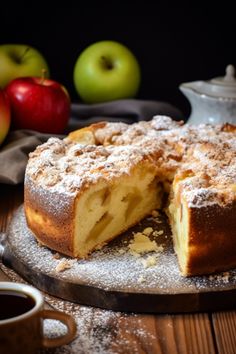 a cake with one slice cut out on a plate next to some apples and a teapot