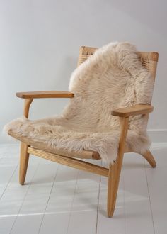 a wooden chair with a sheepskin seat cover on it's back and legs