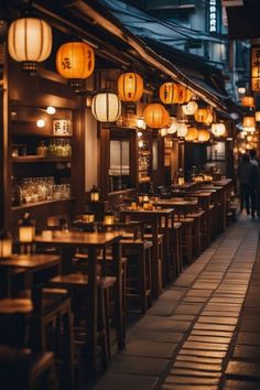 an empty restaurant with lanterns hanging from the ceiling and people walking down the street behind it