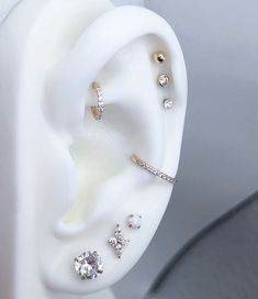 an ear with three different types of piercings on it's sides and two diamonds in the middle