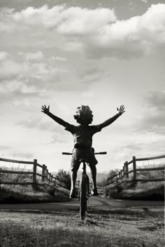 black and white photograph of a person on a bike in the air with their arms outstretched