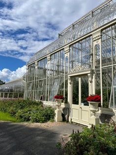 a large white greenhouse with lots of windows and flowers in the planter boxes on each side