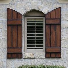 an open window with wooden shutters on a stone building