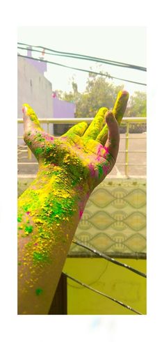 a person's hand covered in yellow and green paint