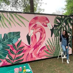 a woman is painting a flamingo mural on the side of a building