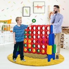 a man standing next to a little boy in front of a giant connect game set